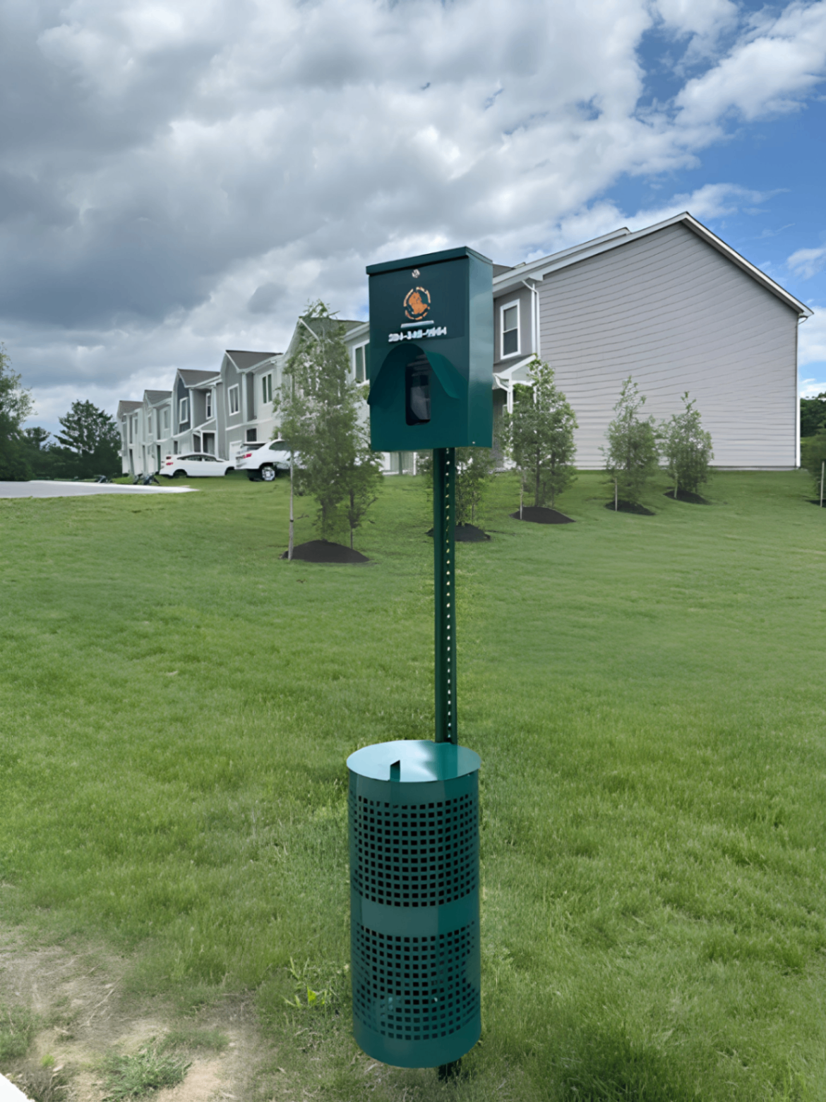 Green pet waste station on a manicured lawn in a townhome community