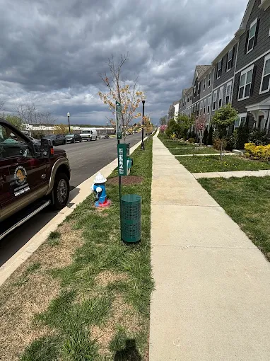 Pet waste station along a community sidewalk with service truck nearby